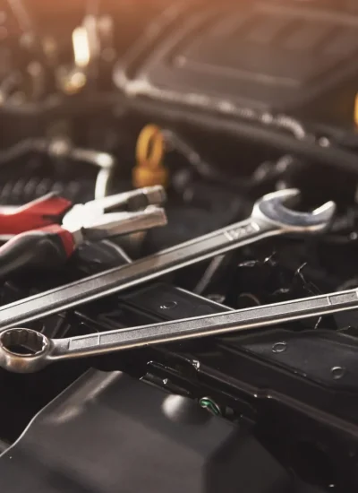 Herramientas de mecánica, incluyendo llaves y alicates, sobre el motor de un automóvil, destacando la importancia del mantenimiento automotriz.